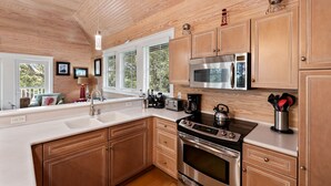 Una cocina con armarios de madera, electrodomésticos de acero inoxidable y un amplio ventanal.