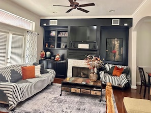A living room with a fireplace, two sofas, a coffee table, and a ceiling fan.
