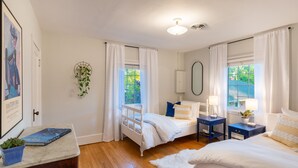 A bedroom with two beds, a bedside table with a lamp, a small plant, and a framed picture on the wall. - Gorgeous Carriage House close to USNA, walk to stadium, free parking,  pets+kids (Annapolis)