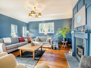 A living room with a sofa, coffee table, fireplace, and a ceiling light fixture.
