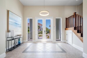 A spacious entryway with a modern staircase, a console table, and a large framed artwork. - Elegant Naples Homes with Private Pool and Steps from Beach by Esthetic Stays (Naples)