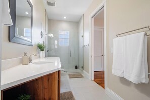 A modern bathroom with two sinks, a glass shower enclosure, and a towel rack.