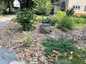 A landscaped garden with various plants, a rock feature, and a paved walkway. - Stylish Lake Harriet home with backyard retreat (Minneapolis)