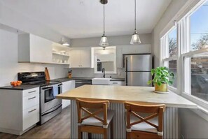 Enjoy cooking in this well-equipped kitchen with a central island, refrigerator, oven, and pendant lighting.