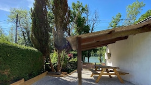 A patio area with a pergola, a picnic table, and a white wall.