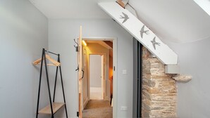Un dormitorio con dos camas, una escalera de madera, una pared de piedra y una escalera decorada con motivos de pájaros.