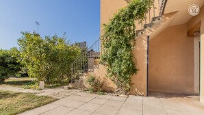A courtyard with a staircase leading to a building, surrounded by trees and a clear sky.