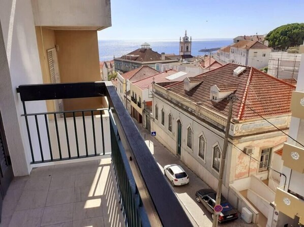 A balcony with a view of a street, buildings, and a church.