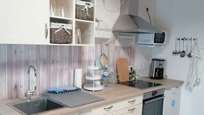 A kitchen with white cabinets, a wooden countertop, a sink, a stove, and a dishwasher.