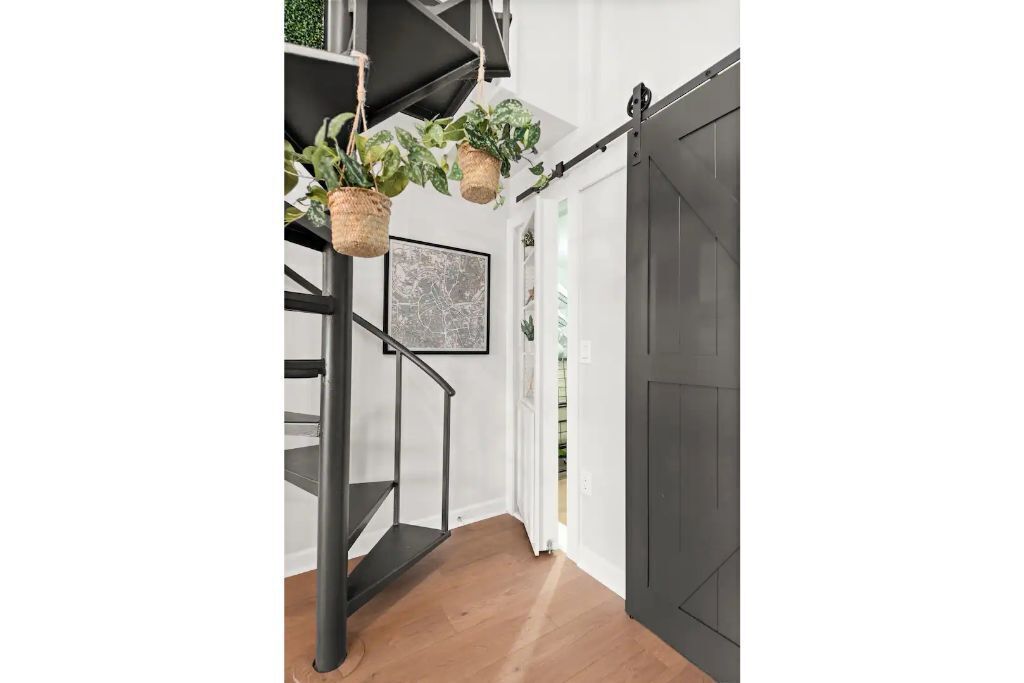 A staircase with black railings, a dark door, and hanging baskets with plants.