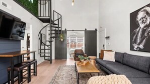 Uma sala de estar moderna com escada, sofá, mesa de centro e televisão.