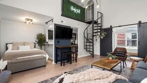 Um espaço de estar moderno com cama, sofá, mesa de centro e escada para um andar superior.