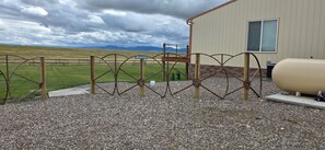 A gravel area with a metal fence, a guest entrance sign, and a building with a window. - Quiet country property, near rivers, complete with farm animals and wildlife.
 (Cascade)