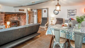 A cozy living room with a fireplace, a dining table with chairs, and a bench.