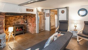 A cozy living room with a stone fireplace, a sofa, and a wooden table with logs.