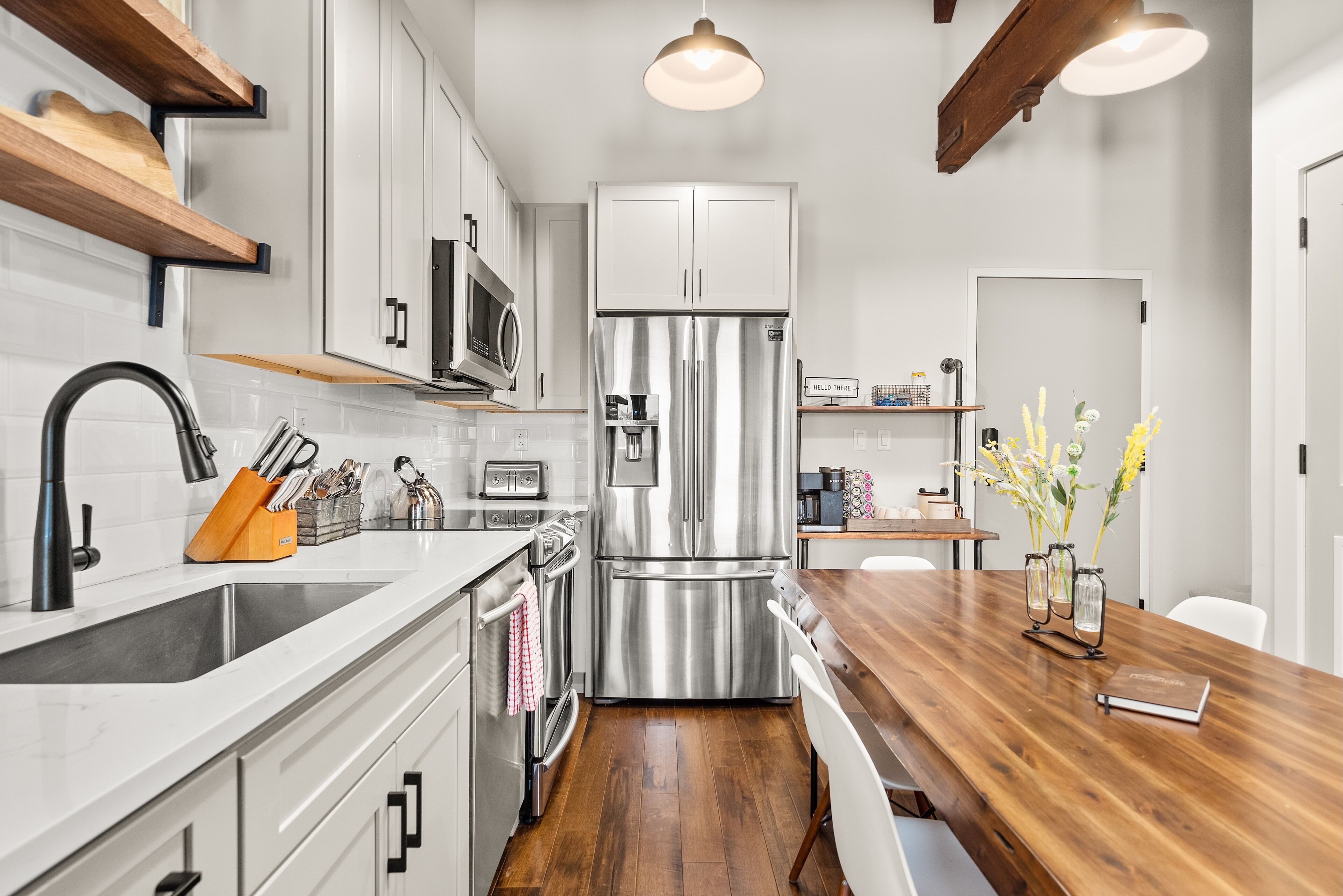 A modern kitchen with stainless steel appliances, a wooden countertop, and a white backsplash.