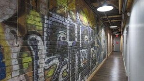 Un pasillo con grafitis en las paredes y suelo de madera.