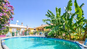 A swimming pool with a slide, surrounded by tropical plants and a yellow building with a tiled roof. - 2 bedroom cozy home in San Nicolao (San Nicolao)