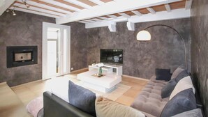 Un salon moderne avec un canapé, une table basse, un téléviseur et une cheminée.