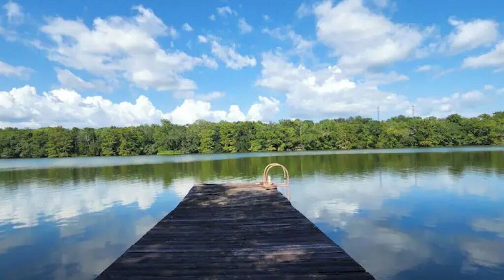 Une jetée en bois s’étendant sur une étendue d’eau calme, sous un ciel dégagé.