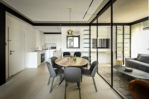 Una cucina moderna con mobili bianchi, un'area pranzo con tavolo e sedie rotonde, e un soggiorno con divano e tavolino.