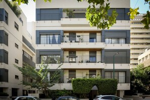 Un edificio residenziale a più piani con balconi, un ingresso centrale e cielo sereno.