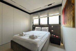 A modern bedroom with a large bed, a nightstand, and a window with curtains.