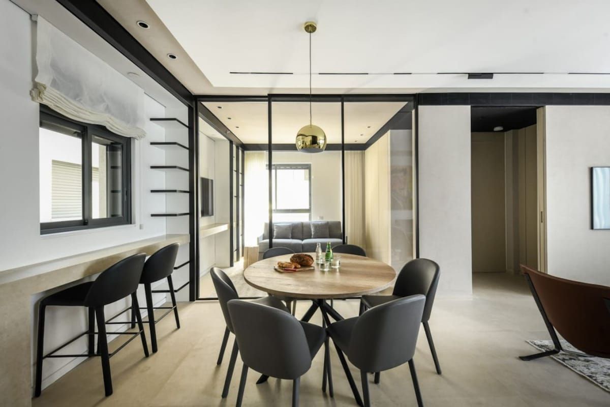 Un espace repas moderne avec une table ronde, des chaises noires et un luminaire suspendu.