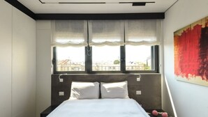 A bed with white bedding, a headboard, and two bedside tables with pink objects on them. - Stylish 2BR with Refined Design & Balcony Charm (Tel Aviv-Yafo)
