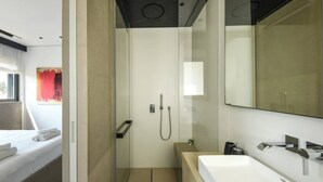 A modern bathroom with a shower, a large mirror, and a white sink. - Stylish 2BR with Refined Design & Balcony Charm (Tel Aviv-Yafo)