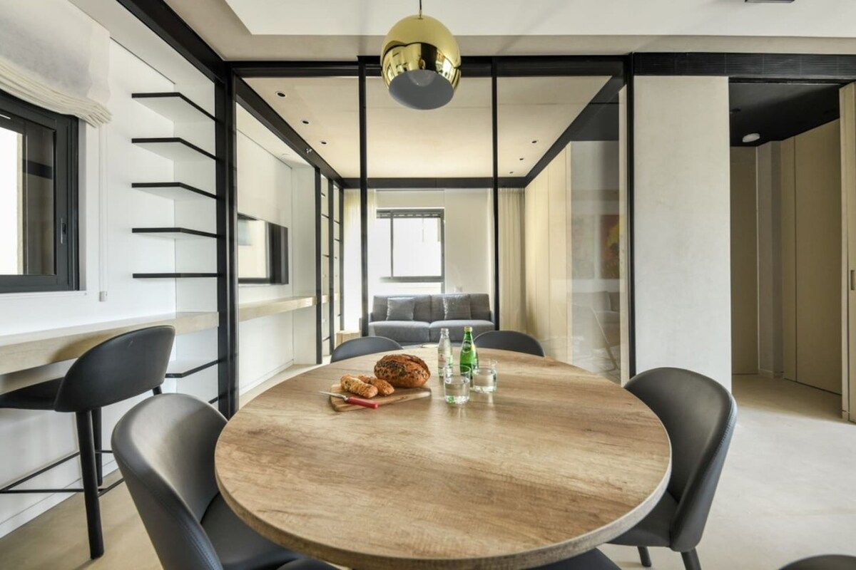 Een moderne eethoek met een ronde tafel, zwarte stoelen en een decoratieve plafondlamp.