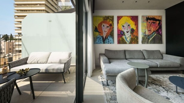 A modern living room with a sofa, a coffee table, and a painting on the wall. - Stylish 2BR with Refined Design & Balcony Charm (Tel Aviv-Yafo)