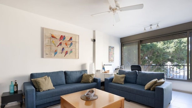 A modern living room with two sofas, a coffee table, and a ceiling fan. - Bright 3BR Stay • Relaxing Comfort (Tel Aviv-Yafo)