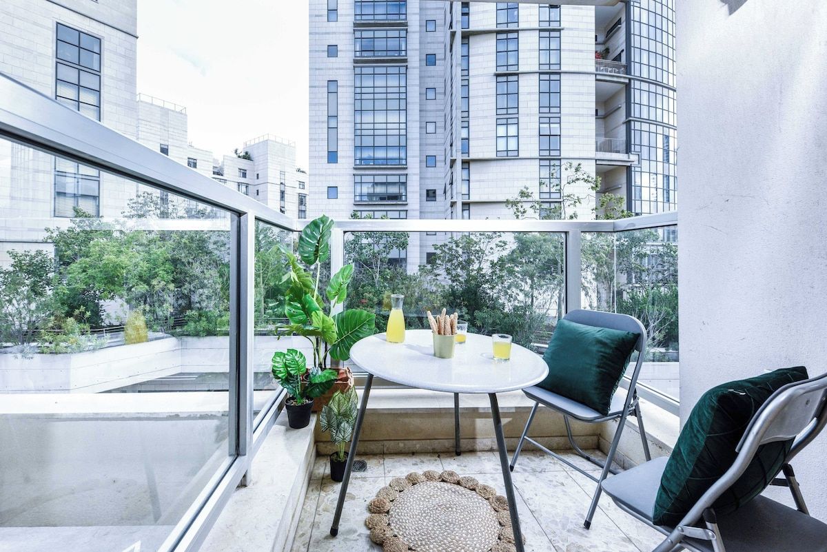 A balcony with a table, chairs, and potted plants.
