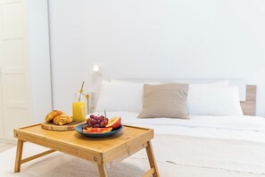 A breakfast tray with croissants, a glass of orange juice, and a plate of fruit on a wooden table in a hotel room.