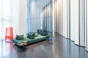 Un intérieur moderne avec un canapé vert, un fauteuil rouge et un mur réfléchissant.