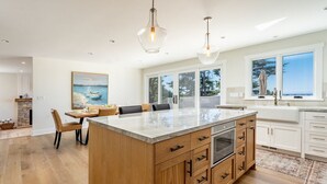 Une cuisine moderne dotée d’un grand îlot central, de meubles en bois et de luminaires suspendus.
