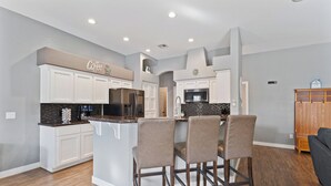 A modern kitchen with white cabinetry, a central island with bar stools, and a built-in oven.