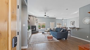 A modern living room with a blue sofa, wooden flooring, and a ceiling fan.