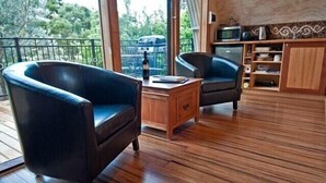 Een kamer met twee leren fauteuils, een houten salontafel en uitzicht op het buitenlands landschap door grote ramen.
