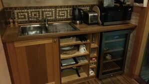 Een kleine keuken met een spoelbak, broodrooster, koffiezetapparaat en een koelkast.
