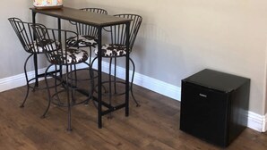 Een eetgedeelte met een tafel, stoelen, een wandbord en een zwart apparaat.
