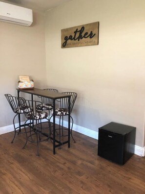 A dining area with a table and chairs, a wall-mounted sign, and a black appliance.