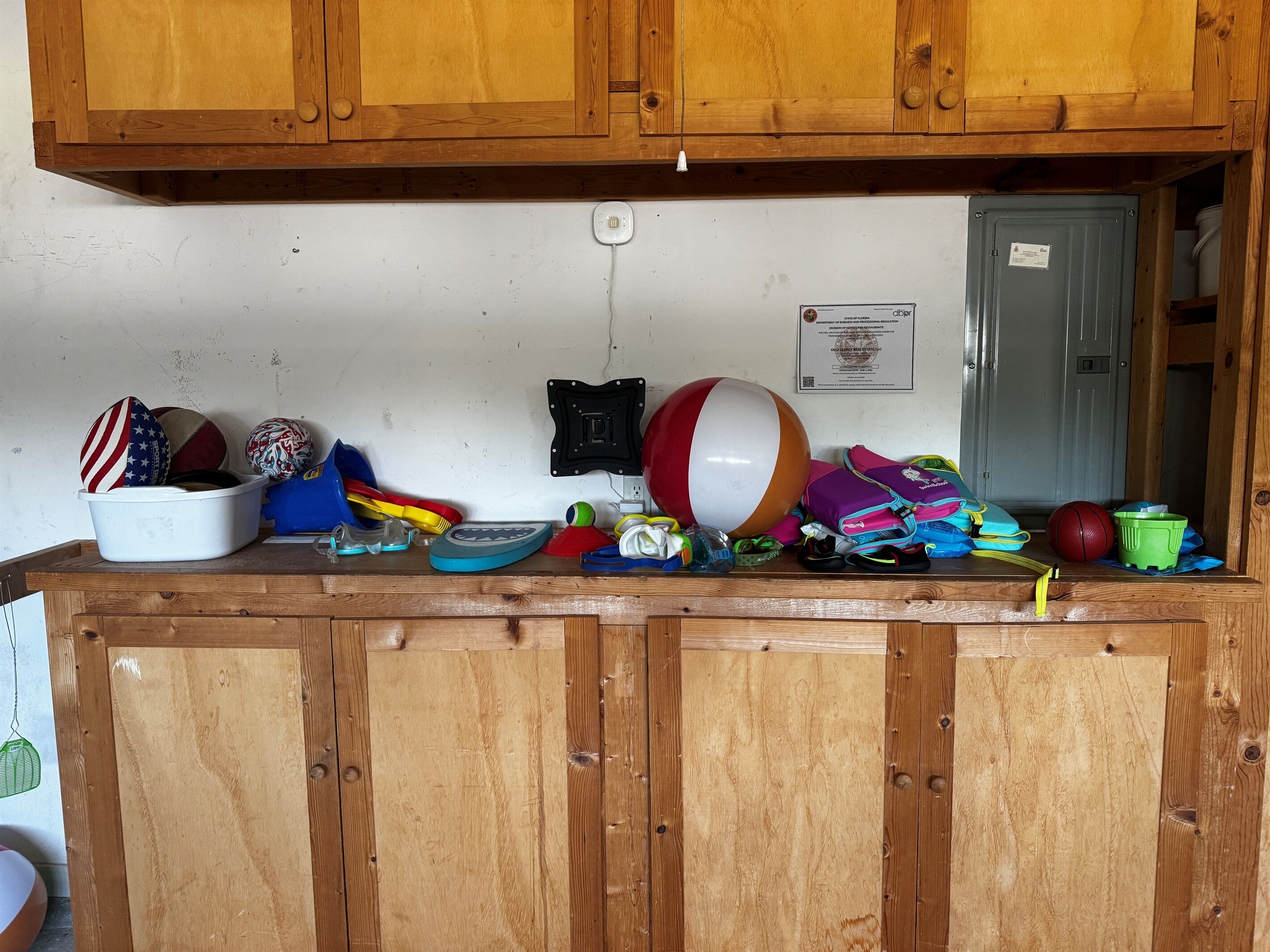 Un comptoir en bois sur lequel sont disposés divers articles, notamment un ballon de plage, du matériel de sport et un seau blanc.