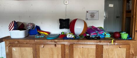 Un comptoir en bois sur lequel sont disposés divers articles, notamment un ballon de plage, du matériel de sport et un seau blanc.