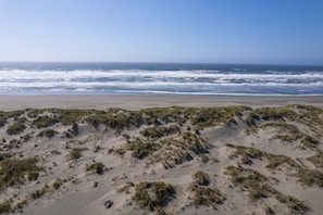 A beach with sand dunes and ocean waves.