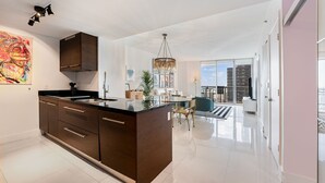 A modern kitchen with dark wooden cabinets, a central island, and a dining area with a chandelier.