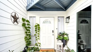 A white door with a welcome mat, a star decoration, and potted plants. - Modern Boho Retreat W/3 Spacious Bedrooms +3Bathrooms +Garage (Houston)