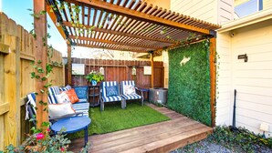A wooden pergola with a green wall and a seating area with two chairs and a table. - Modern Boho Retreat W/3 Spacious Bedrooms +3Bathrooms +Garage (Houston)