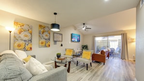 A living room with a gray sofa, yellow cushions, a glass coffee table, and a ceiling fan. - Modern Boho Retreat W/3 Spacious Bedrooms +3Bathrooms +Garage (Houston)